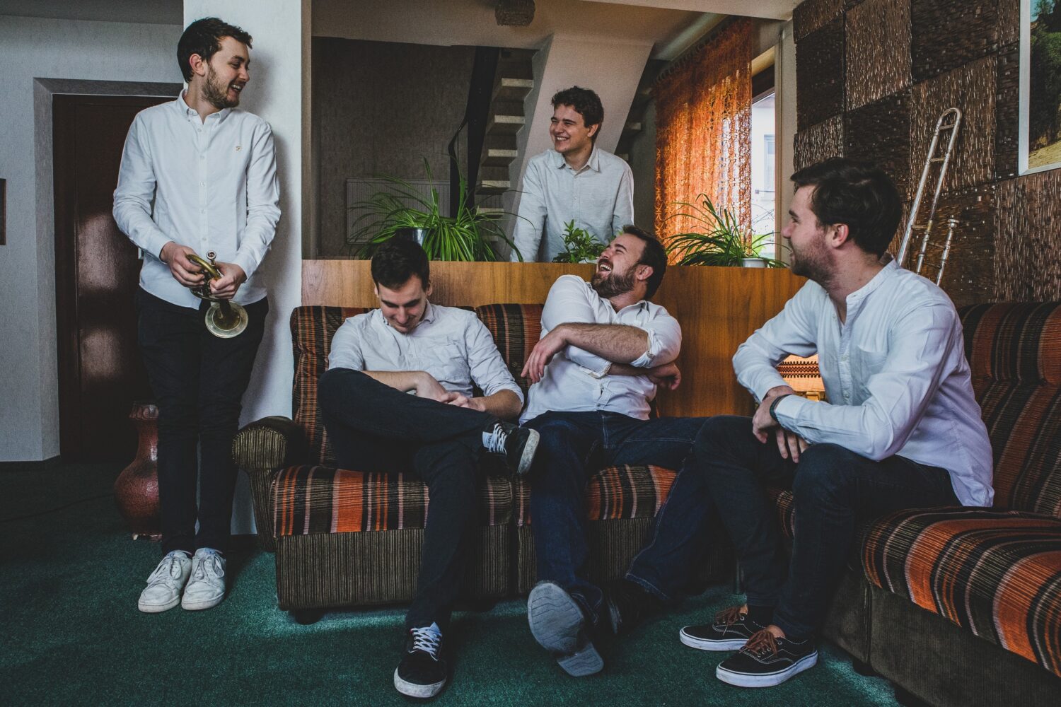 Gruppe von Männern auf Couch im Wohnzimmer. Sie lachen.